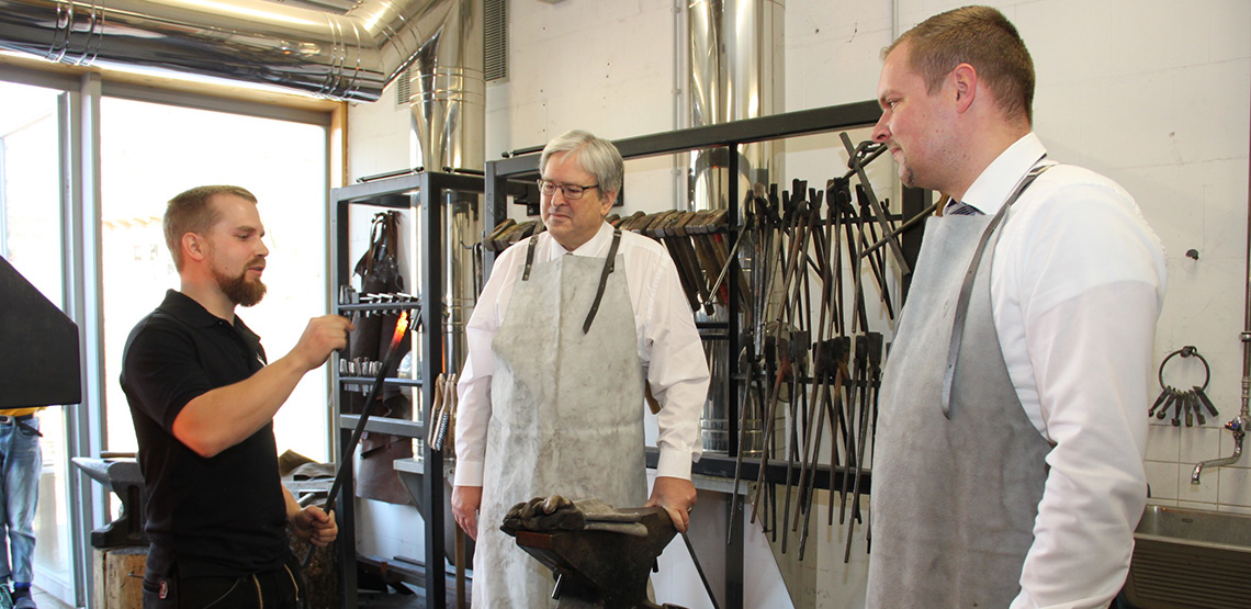 Minister Steinbach und Handwerkskammertagspräsident Wüst (r.) schmieden unter Anleitung von Metallbaumeister Fritz Kassek (l.) in der Lehrschmiede der Walldorfschule Kleinmachnow. Foto: MWE